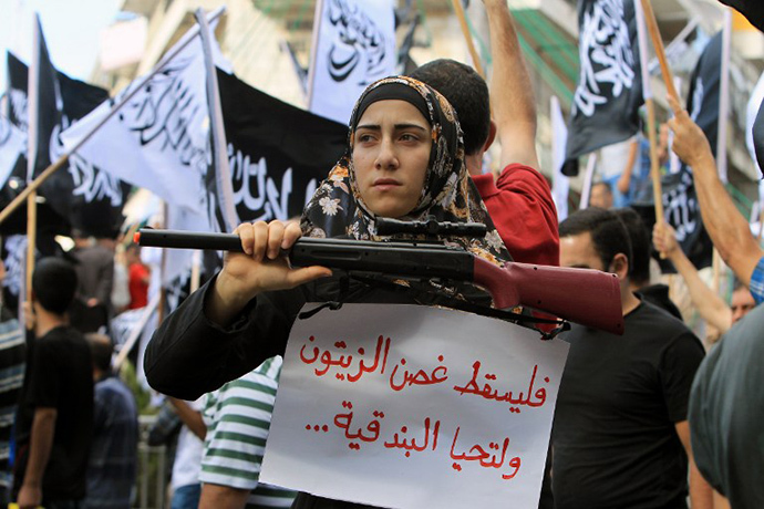 A Palestinian protester holds a placard and a fake weapon during a demonstration to support the resistance in Gaza and to protest against the Israeli military offensive on the Palestinian Gaza Strip on July 20, 2014 in the West Bank city of Ramallah. (AFP Photo / Abbas Momani)