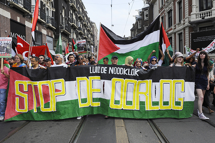 Protesters carry a banner depicting the Palestinian flag reading "Sound the alarm, Stop the War" as they take part in a demonstration in Amsterdam on July 20, 2014, to protest Israel's military campaign in Gaza and show their support for the Palestinian people. (AFP Photo / John Thys)