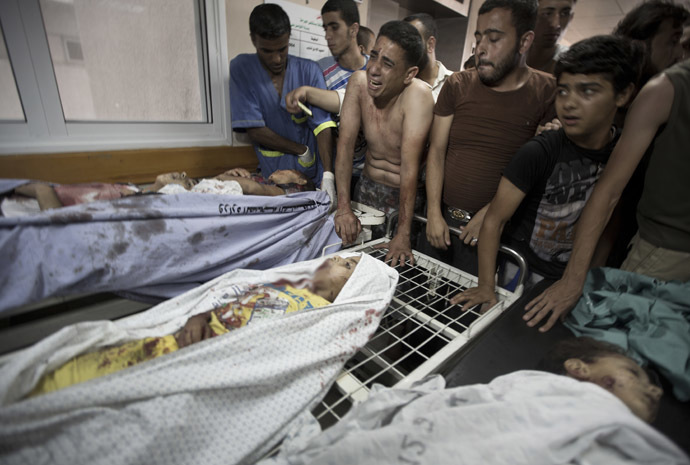 Palestinian mourners and medics gather over the bodies of six of the eight children who were killed in an explosion in a public playground in the beachfront Shati refugee camp in Gaza City on July 28, 2014. (AFP Photo/Mahmud Hams)