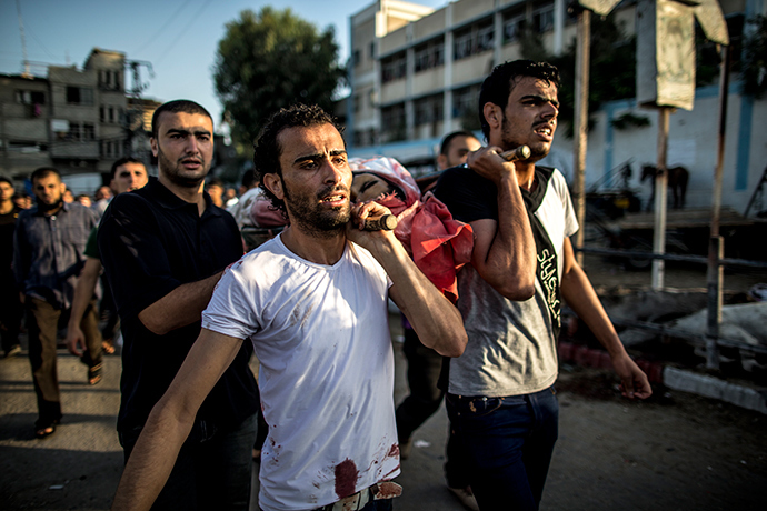 Palestinian mourners carry a body as they walk during a funeral procession past a UN school that was hit by Israeli shelling in the Jabalia refugee camp on July 30, 2014 (AFP Photo / Marco Longari)