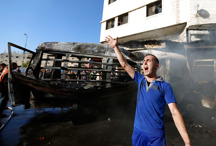 A Palestinian shouts slogans as firefighters try to extinguish the flames in a van, that was reportedly targeted by an Israeli military strike, in Gaza City on July 31, 2014. (AFP Photo / Mohammed Abed)