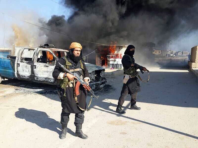 An image uploaded to an Islamic website on January 8, 2014, allegedly shows Shakir Wahib (L), Abu Wahib, a leader of the Islamic State of Iraq and the Levant (ISIS) standing next to burning cars (AFP Photo)