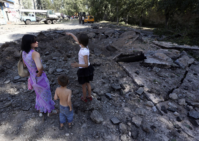 Local residents stand in a crater following what locals say was recent airstrike by Ukrainian forces in Donetsk, August 6, 2014. (Reuters/Sergei Karpukhin)