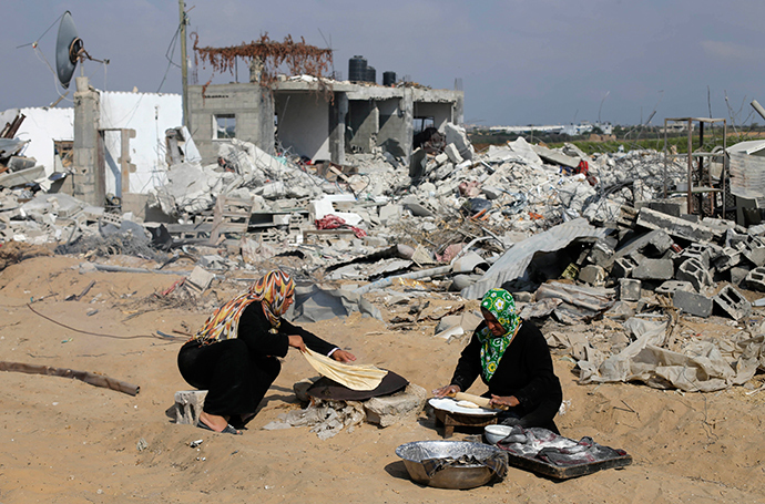 Palestinian women bake bread in front of the remains of their house, which witnesses said was destroyed in the Israeli offensive, during a 72-hour truce in Khan Younis the southern Gaza Strip August 13, 2014 (Reuters / Ibraheem Abu Mustafa)