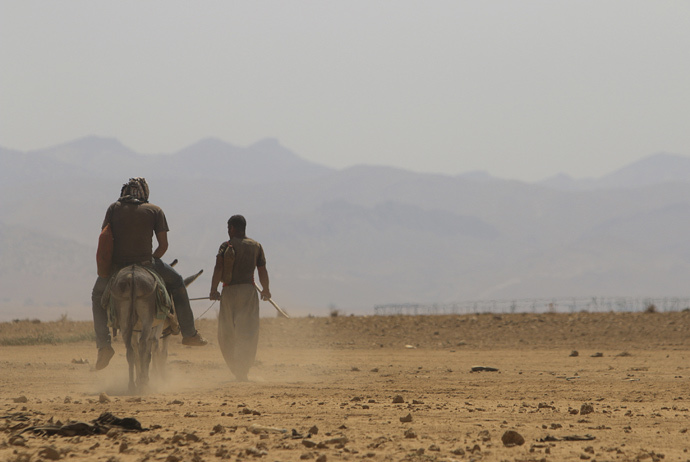 A displaced man from the Yazidi religious minority, fleeing violence from forces loyal to the Islamic State in Sinjar town, rides a donkey as he makes his way with another man towards the Mount Sinjar, after securing the evacuation process of their families towards the Syrian border August 13, 2014. (Reuters / Rodi Said)