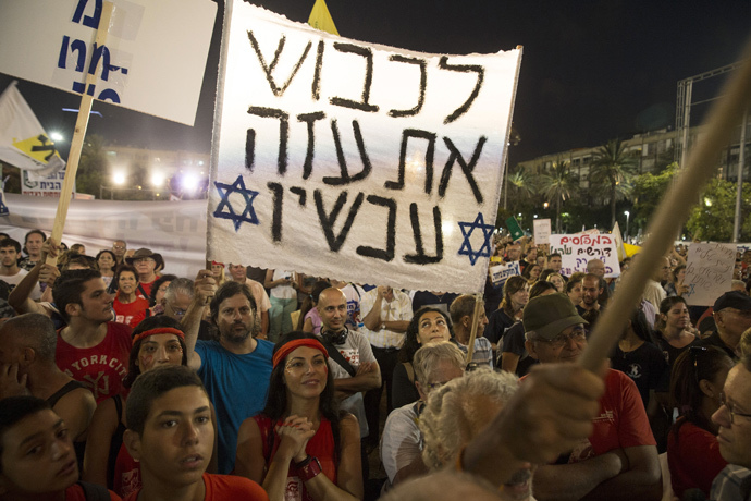 People hold signs during a rally in Tel Aviv's Rabin Square, to show solidarity with residents of Israel's southern communities, who have been targeted by Palestinian rockets and mortar salvoes, August 14, 2014. The sign reads "Conquer Gaza now". (Reuters / Baz Ratner)