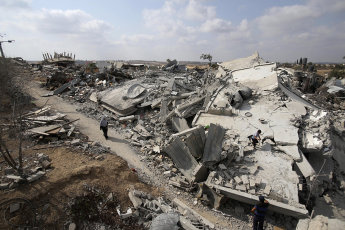 A Palestinian woman walks past the ruins of houses which witnesses said were destroyed during the Israeli offensive in Johr El-Deek village near the central Gaza Strip August 17, 2014. (Reuters / Ibraheem Abu Mustafa)