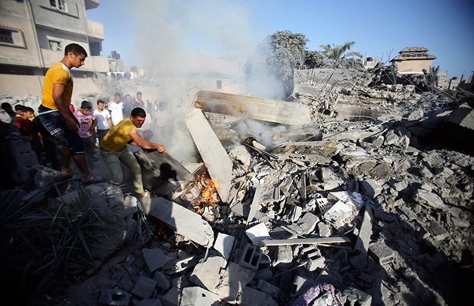 Palestinians try to put out a fire from the rubble of a house, which witnesses said was destroyed in an Israeli air strike, in Rafah in the southern Gaza Strip August 20, 2014 (Reuters / Ibraheem Abu Mustafa)