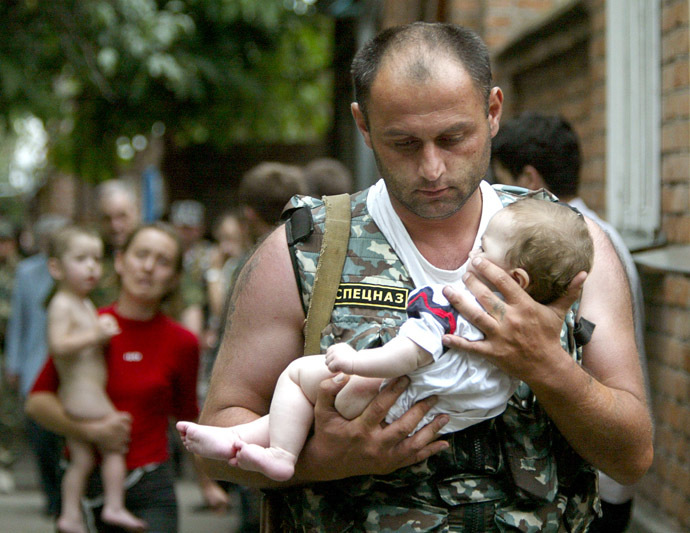 Russian police officer carries a released baby from the school seized by heavily armed masked men and women in the town of Beslan. (Reuters/Viktor Korotayev)