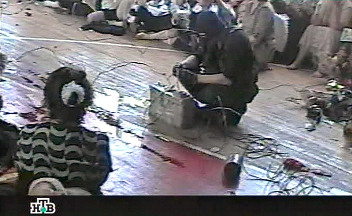 This TV grab image taken from Russian NTV channel 07 September 2004 shows a gunman connecting wires as hostages sit in the gymnasium of the Beslan school, northern Ossetia. (AFP/NTV)