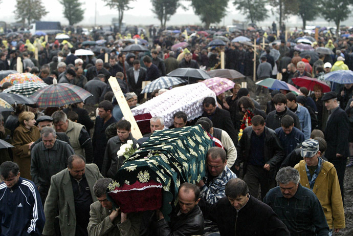 Relatives of victims who died in the Beslan school hostage siege carry coffins under the heavy rain at the cemetery in Beslan, North Ossetia, 06 September 2004. (AFP Photo/Viktor Drachev)