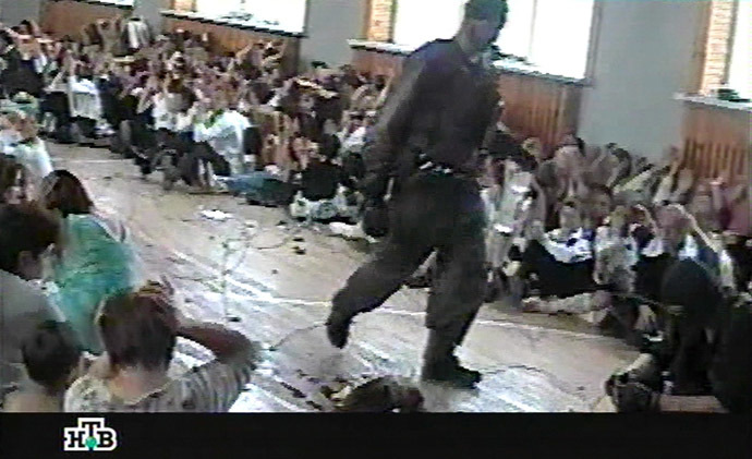 This TV grab image taken from Russian NTV channel 07 September 2004 shows a gunman walking as hostages sit in the gymnasium of the Beslan school, northern Ossetia. (AFP/NTV)