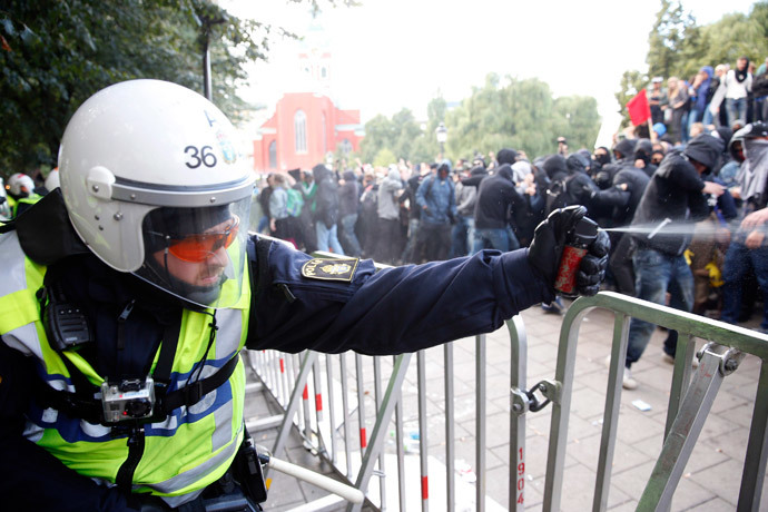 A police officer uses a spray during clashes with demonstrators protesting against an election meeting organised by right-wing political group The Party of the Swedes (Svenskarnas Parti), at the Kungstradgarden square in central Stockholm August 30, 2014. (Reuters / Fredrik Persson)