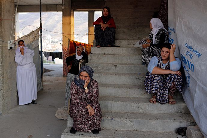 Displaced people from the minority Yazidi sect who fled the violence in the Iraqi town of Sinjar, wait for aid at an abandoned building that they are using as their main residence, outside the city of Dohuk (Reuters / Youssef Boudlal)