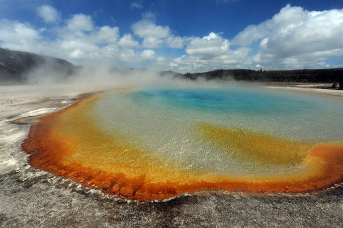 View of the 'Sunset Lake' hot spring with it's unique colors caused by brown, orange and yellow algae-like bacteria called Thermophiles, that thrive in the cooling water turning the vivid aqua-blues to a murkier greenish brown, in the Yellowstone National Park, Wyoming. (AFP Photo / Mark Ralston)