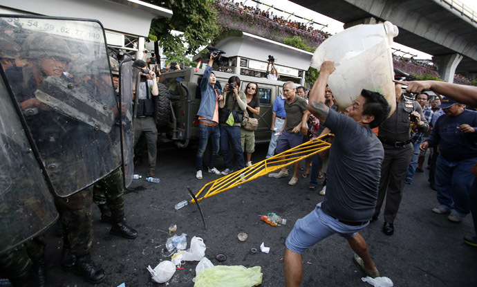 A protester against military rule throws a plastic garbage bin at soldiers during a scuffle at Victory Monument in Bangkok May 28, 2014. (Reuters)