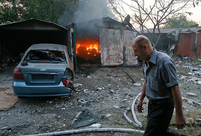 A man walks past a garage set ablaze by what locals say was shelling by Ukrainian forces in Donetsk, September 4, 2014 (Reuters / Maxim Shemetov)