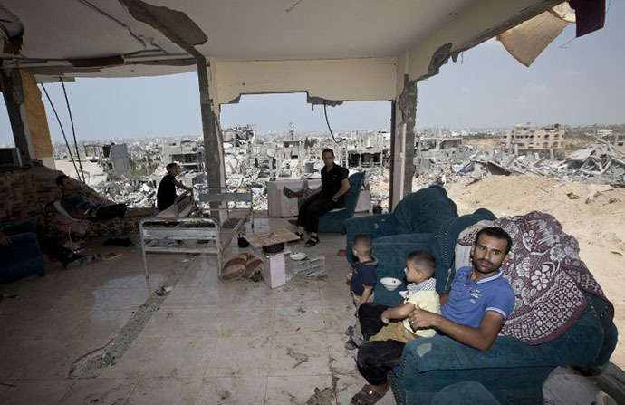 Palestinians sit inside their destroyed house after returning home in the Tufah neighbourhood in eastern Gaza City on August 31, 2014. (AFP Photo / Mahmud Hams)