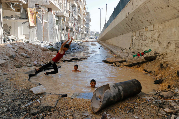 A boy dives into a crater filled with water in Aleppo's al-Shaar district, Syria (Reuters / Hosam Katan)