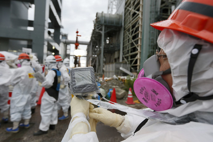A Tokyo Electric Power Co. (Tepco) employee measures radiation levels as workers conduct operations to construct an underground ice wall at Tepco's tsunami-crippled Fukushima Daiichi nuclear power plant in Fukushima Prefecture July 9, 2014. (Reuters/Kimimasa Mayama)