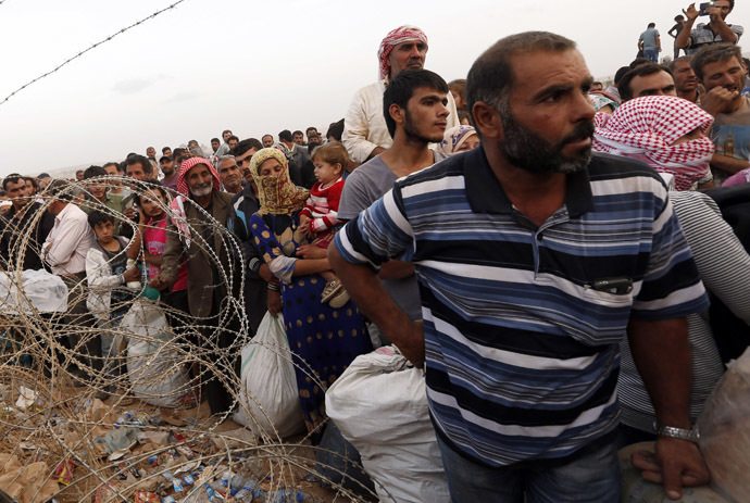 Syrian Kurdish refugees wait behind the border fences to cross into Turkey near the southeastern town of Suruc in Sanliurfa province September 27, 2014. (Reuters/Murad Sezer)