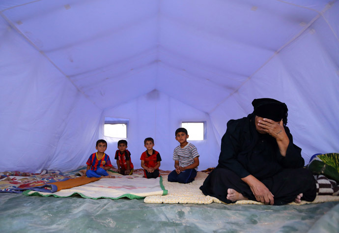 A family, who fled from the violence in Mosul, sits inside a tent at a camp on the outskirts of Arbil in Iraq's Kurdistan region, June 12, 2014. (Reuters / Stringer)