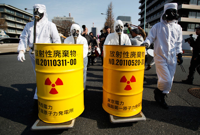 Anti-nuclear protesters wearing protective suits push mock drums which are labelled as radioactive waste from Kansai Electric Power Co's Ohi nuclear power plant (L) and Tokyo Electric Power Co's (TEPCO) Fukushima nuclear power plant, as they march in Tokyo March 9, 2014.(Reuters / Yuya Shino )