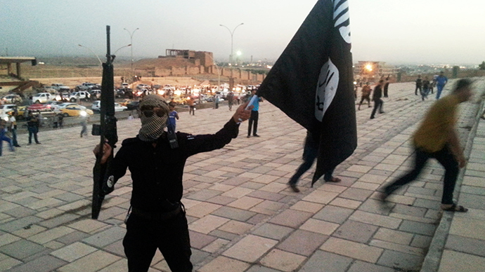 A fighter of the Islamic State of Iraq and the Levant (ISIL) holds an ISIL flag (Reuters / Stringer)