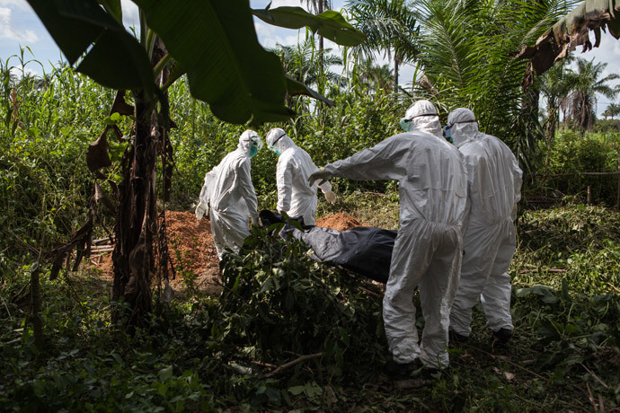 A specialized Ebola inhumation team carry the body of a recent Ebola victim to be buried, on October 6, 2014 in Magbonkoh. (AFP Photo / Florian Plaucheur)