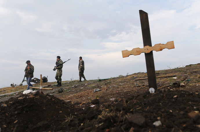 Militia members walk past an unmarked grave at Savur-Mohyla, a hill east of the city of Donetsk, August 28, 2014. (Reuters/Maxim Shemetov)