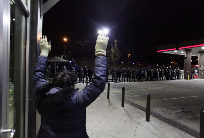 A demonstrator protesting the shooting death of Michael Brown and 18-year-old Vonderrit Myers Jr. holds her hands in the air as she looks at police officers in riot gear at a QuikTrip convince store and gas station October, 12 2014 in St. Louis, Missouri. (AFP Photo/Joshua Lott)