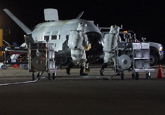 Personnel in self-contained atmospheric protective ensemble suits conduct initial checks on the X-37B Orbital Vehicle (Reuters / HO)