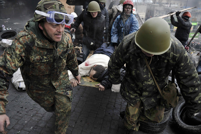 Protesters carry a wounded protester during clashes with polie, after gaining new positions near the Independence square in Kiev on February 20, 2014.(AFP Photo/Louisa Gouliamaki)