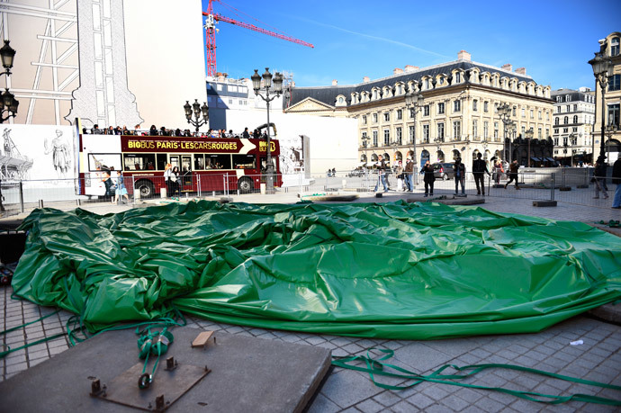 The controversial, inflatable sculpture "Tree" by US artist Paul McCarthy sits deflated on the Vendome square in the center of Paris on October 18, 2014 after people sectionned overnight the cables securing it to the ground and tampered with the pump keeping it inflated. (AFP Photo / Martin Bureau)