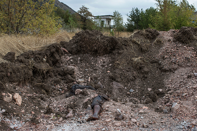 A dismembered body lies on a site where rebels say is a mass grave with five bodies in the town of Nizhnya Krynka, eastern Ukraine, September 23, 2014 (Reuters / Marko Djurica)