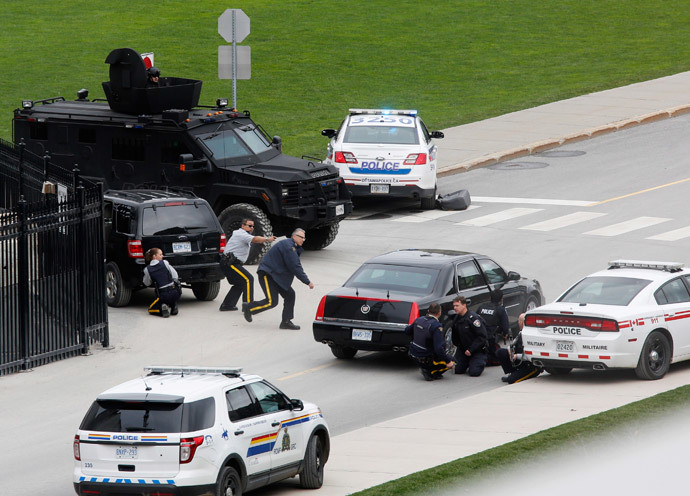 Police officers take cover near Parliament Hill following a shooting incident in Ottawa October 22, 2014.(Reuters / Chris Wattie)