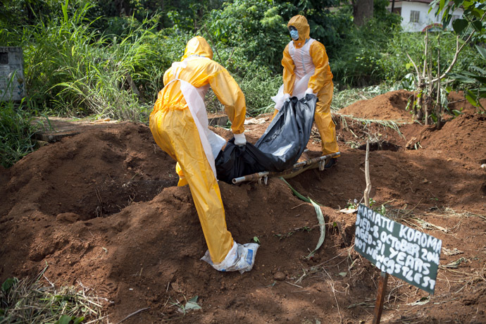 A team of funeral agents specialised in the burial of victims of the Ebola virus put a body in a grave at the Fing Tom cemetery in Freetown, on October 10, 2014. (AFP Photo)