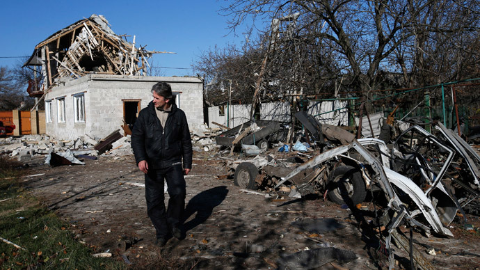 A man walks past a residential block and a car damaged by recent shelling in Donetsk, eastern Ukraine.(Reuters / Maxim Zmeyev)