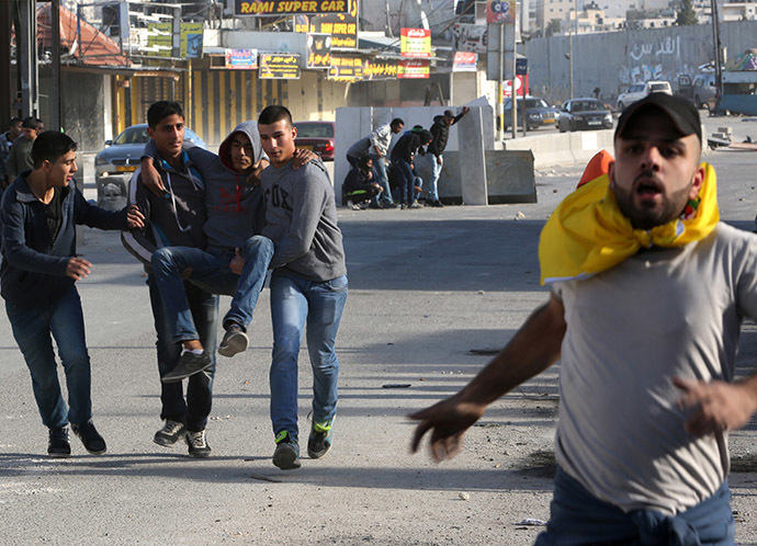 Palestinian youths evacuate a comrade who was injured during clashes with Israeli security forces at the Israeli Qalandia checkpoint between the West Bank city of Ramallah and Jerusalem on November 7, 2014. (AFP Photo/Abbas Momani)