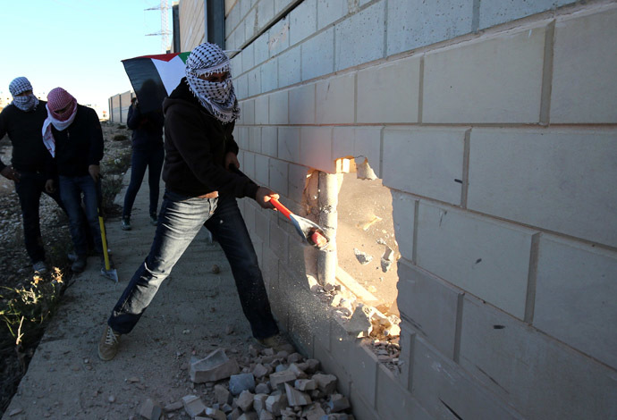 Palestinian youths use sledgehammers to break parts from a concrete segment of the controversial Israeli separation wall in the West Bank village of Bir Nabala -between Jerusalem and Ramallah- on November 8, 2014 as celebrations today mark 25 years since the fall of the Berlin Wall. (AFP Photo)