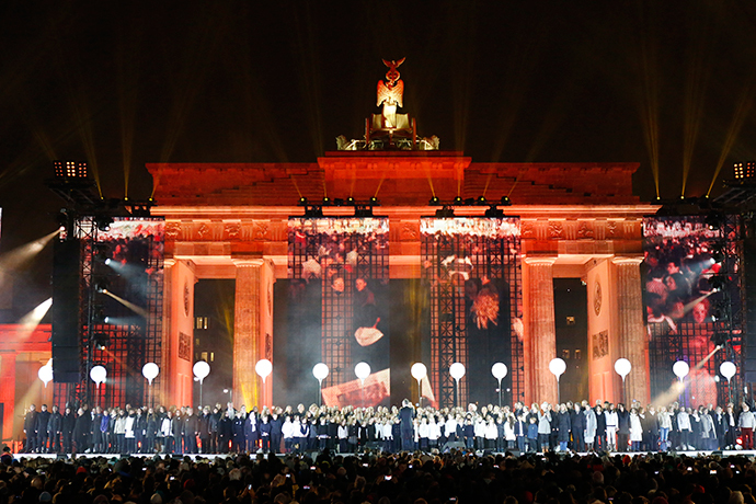 A choir performs on stage in front of the Brandenburg Gate next to part of the installation 'Lichtgrenze' (Border of Light) in Berlin, November 9, 2014. (Reuters / Fabrizio Bensch)