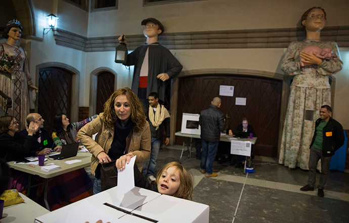 A child deposits her mother's ballot at a polling station in a school in front of Catalan "Gegants", or giant figures, while voting in a symbolic independence vote in Barcelona, November 9, 2014. (Reuters / Paul Hanna)