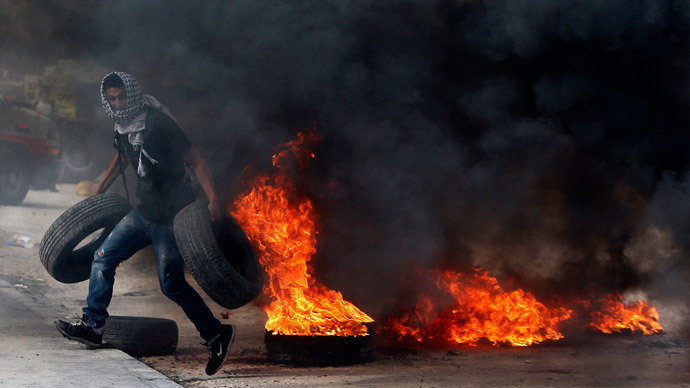 A Palestinian protester carries tyres during clashes with Israeli troops following an anti-Israel demonstration over the recent entry restrictions to the al-Aqsa mosque, at Qalandia checkpoint, near the West Bank city of Ramallah November 2, 2014. (Reuters / Ammar Awad)