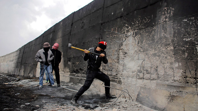 A Palestinian protester tries to hammer a hole through Israel's controversial barrier that separates the West Bank town of Abu Dis from Jerusalem November 17, 2014. (Reuters / Ammar Awad)
