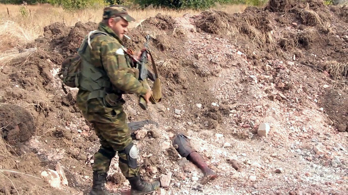 A Donetsk People's Republic militiaman is at the site of the graves of peaceful residents discovered near Mine 22 "Kommunar" outside Donetsk (stills from video courtesy of the Ruptly)