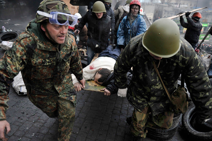 Protesters carry a wounded protester during clashes with poliÑe, after gaining new positions near the Independence square in Kiev on February 20, 2014. (AFP PHhoto / Louisa Gouliamaki)