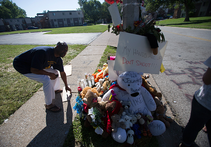 A man picks up a sign that fell from a makeshift memorial near where black teenager Michael Brown was shot to death by police over the weekend in Ferguson, Missouri August 12, 2014 (Reuters / Mario Anzuoni)