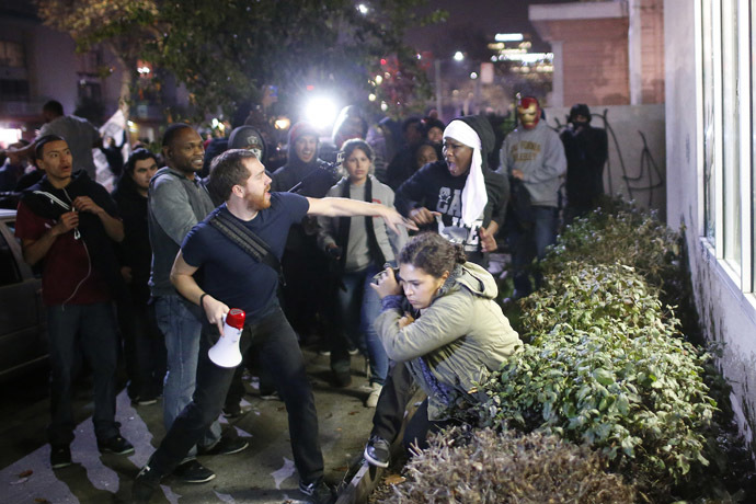 A man attempts to stop a protester from confronting another protester (bottom), who fell into the bushes while trying to protect a convenience store, during a demonstration following the grand jury decision on Monday in the Ferguson, Missouri shooting of Michael Brown, in Oakland, California, November 26, 2014. (Reuters/Stephen Lam)