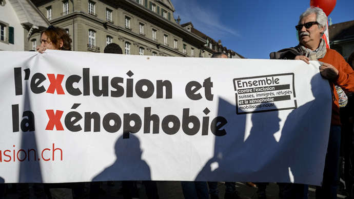 A man holds a banner reading in French "Together against exclusion and xenophobia, Swiss, immigrants, refugees let us unite!" during a demonstration in Bern against an initiative that wants to curb immigration and promote birth control in developing countries on November 1, 2014.(AFP Photo / Fabrice Coffrini)