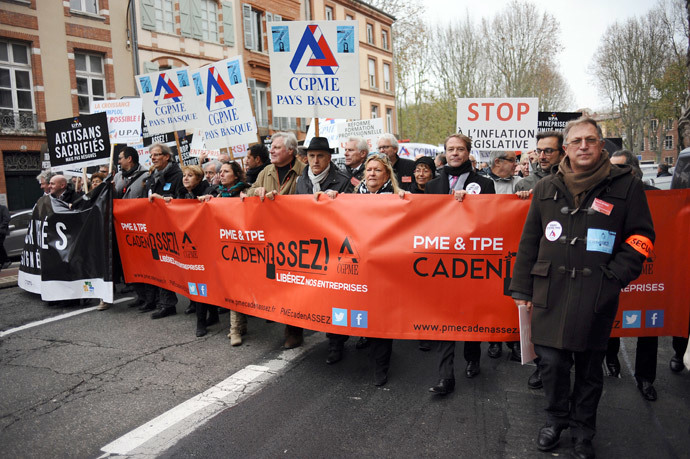 French business owners hold signs of the "Confederation Generale des Petites et Moyennes Entreprises" (CGPME) as they protest on December 1, 2014 in Toulouse against hefty taxes, charges and stifling regulations they say are driving their firms into the ground. (AFP Photo / Remy Gabalda)